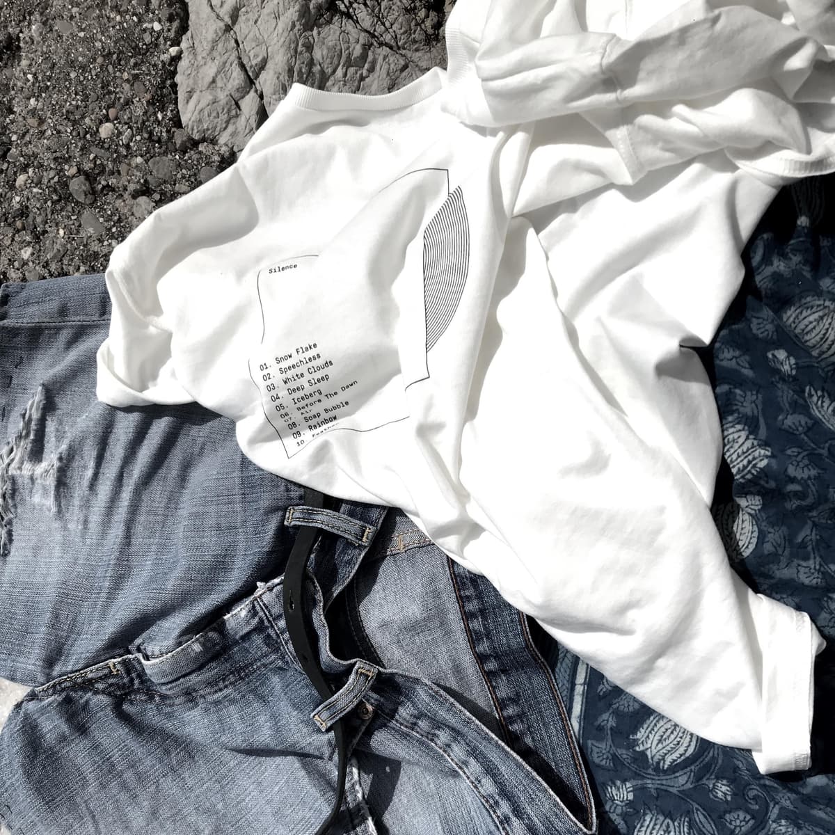 White tee-shirt with a simple design on it, representing a vinyle record whose album name is Silence, and a list of 10 tracks.